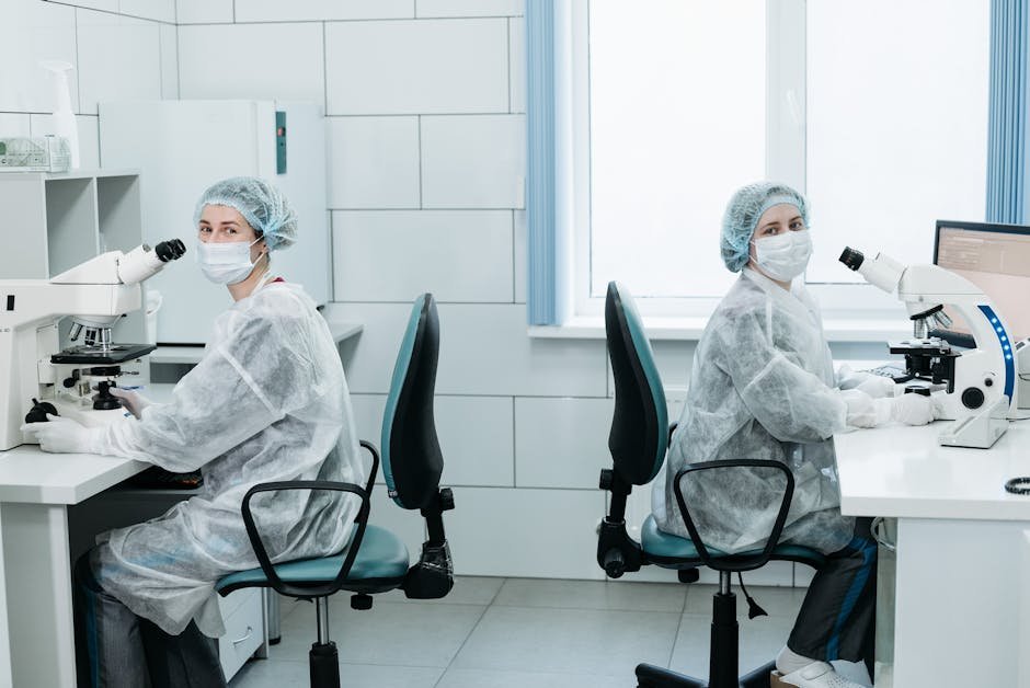 Two female scientists working with microscopes in a laboratory setting.